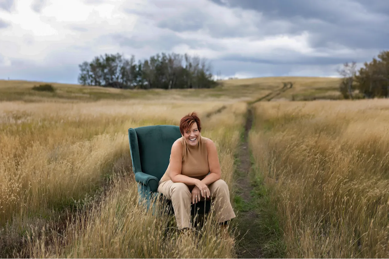 Carla White sitting in a green chair in a sunlit field